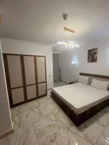 a bedroom with a large bed and a chandelier at اهرمات بورتو السخنه in Madinaty