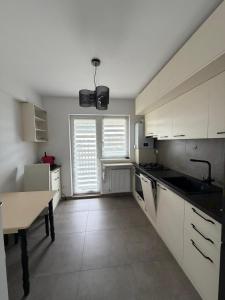 a kitchen with white cabinets and a table in it at Elite Noua in Braşov +5 photos