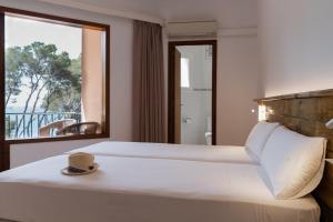 a bedroom with a bed and a window with a view at Hostal Palmaria in Cala Santanyi
