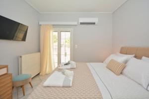 a white bedroom with a bed and a television at Vista Mare I in Porto Heli