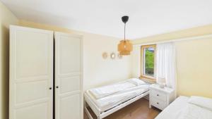 a white bedroom with a bed and a window at Casa Terza - CharmingStay in Flumserberg