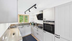 a white kitchen with white cabinets and a sink at Casa Terza - CharmingStay in Flumserberg +5 photos