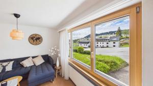 a living room with a couch and a large window at Casa Terza - CharmingStay in Flumserberg