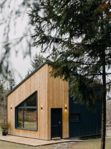 a wooden building with a black door and a tree at Monside Resort - EARTH CABIN in Borzont