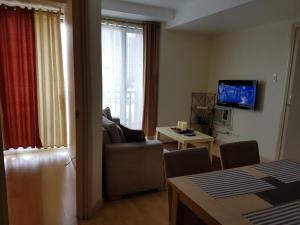 a living room with a couch and a television at ORTIGAS 2 Br Corner Unit With 2 Queen Across Shangrila in Manila