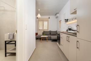 a kitchen with white cabinets and a living room at Stay in Falassarna Rooms & Apartments in Falasarna