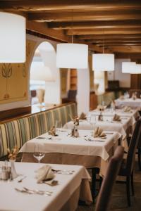a row of tables in a restaurant with white table settings at Hotel Ludwigshof & Luvina in Trodena
