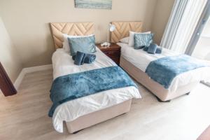two beds in a bedroom with blue pillows at Beach View Apartment 205 in Swakopmund +12 photos