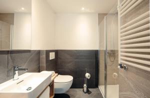 a bathroom with a toilet and a sink and a shower at Hotel Ludwigshof & Luvina in Trodena +8 photos