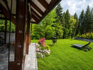 a patio with a bench and a grass yard at Biały Domek Świerczek - Jacuzzi, Balia Ruska SPA, Rowery, Altana i Grill w Słopnice in Słopnice