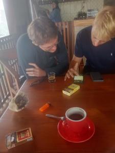 two people sitting at a table with a cup of coffee at Chepclean in Kelimutu