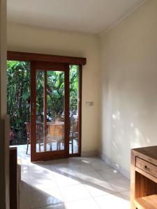 an empty room with a sliding glass door with a table at Nataliya Homestay in Ubud