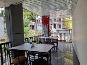two tables and chairs on a balcony with a clock at Hotel Rajinder Prasth in Dalhousie
