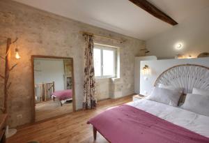 a bedroom with a large bed and a mirror at Small country house with authentic charm in Baurech