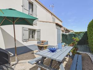 a picnic table with an umbrella in the backyard of a house at La Tranche-sur-Mer, maison pour 3 adultes-2 enfants in La Tranche-sur-Mer