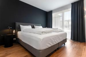a bedroom with a bed with white sheets and a window at B2 Apartments by Heimaleiga in Reykjavík