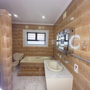 a bathroom with a tub and a toilet and a sink at Cozy Villa Lodge in Edenvale +62 photos