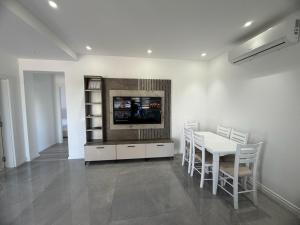 a dining room with a table and a tv on a wall at Holliday Villa in Tirana