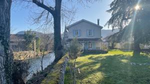 a white house sitting on the side of a river at Au moulin d'Izaourt in Izaourt