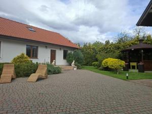 a patio with two chairs and a house at Biały Domek dla 8 osób oraz Domek Sternika dla 4 osób - jezioro, las, wiejski klimat in Międzychód