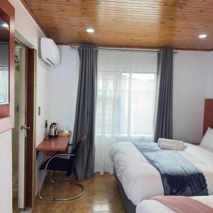 a bedroom with two beds and a desk and a window at Cozy Villa Lodge in Edenvale