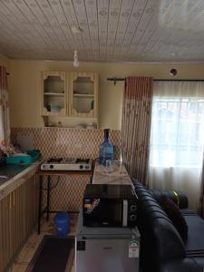a kitchen with a couch and a table with a microwave at Rosemond cottages eldoret in Eldoret +6 photos