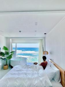 a woman sitting on a bed in a bedroom with a tub at Gangneung The View Pension in Gangneung
