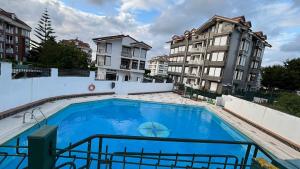 a large blue swimming pool with two tall buildings at piso en la playa in Noja