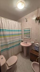 a bathroom with a sink toilet and a shower curtain at piso en la playa in Noja +17 photos