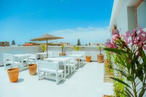 a patio with white chairs and tables and an umbrella at Salty in Essaouira