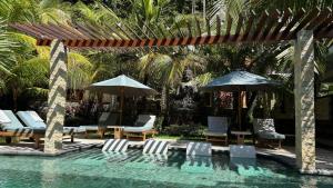 a swimming pool with lounge chairs and umbrellas at ABG Villas - Agrowisata Amed in Amed