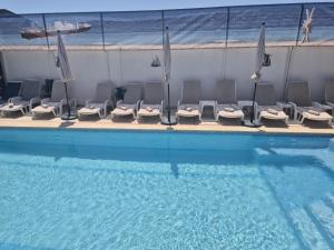 a pool with chairs and umbrellas next to a swimming pool at Vila Paun in Costinesti