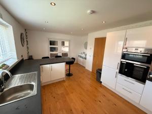 a kitchen with white appliances and a wooden floor at 6 Pegasus Place in Lerwick