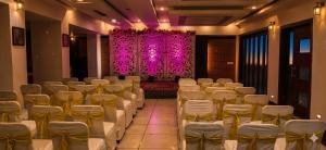 a banquet hall with white chairs and a purple curtain at Hotel Golden Manor-City Center Bani Park in Jaipur