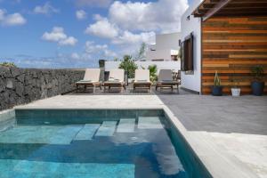 a swimming pool with chairs and a house at Casa Andrada in Yaiza