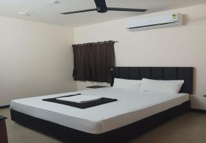 a bedroom with a bed with white sheets and a ceiling at Nandha Grande Elite in Udumalaippettai +4 photos