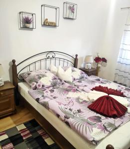 a bed with a pink and white blanket and pillows at Era Apartmanház in Harkány