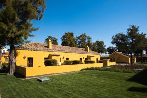a house with a yellow wall and a yard at Vila Gale Albacora in Tavira