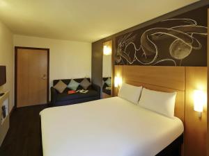 a hotel room with a large white bed and a couch at ibis Reading Centre in Reading +47 photos