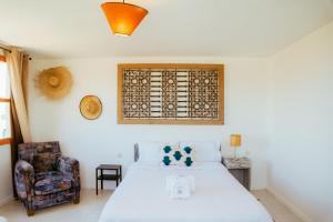 a bedroom with a white bed and a chair at Salty in Essaouira +66 photos