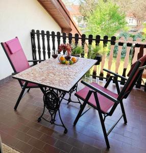 a table with a bowl of fruit and two chairs at Era Apartmanház in Harkány +88 photos