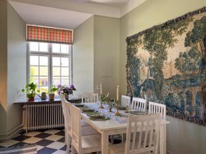 a dining room with a table and a large tapestry at Guest apartment in the castle in Höör