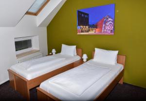 two beds in a room with a green wall at Apartmány U Gigantu in Pilsen