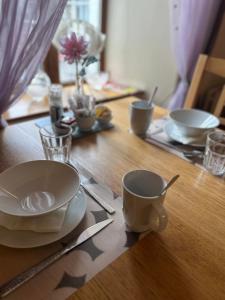 a table with plates and cups on a wooden table at O'Domhnaill's Guesthouse - Lig do Scíth in Galway