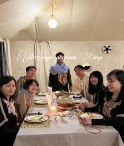 a group of people sitting around a table in a tent at Merzouga premium Camp in Merzouga