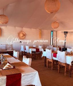 a dining room with tables and chairs and a sign at Merzouga premium Camp in Merzouga