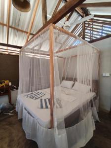 a canopy bed with mosquito nets in a room at Upali Beach Surf Resort in Nikawatawana