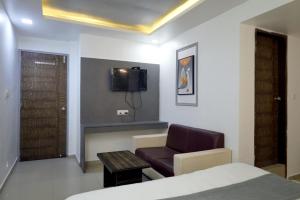 a bedroom with a bed and a chair and a tv at HOTEL GOLD LEAF in Ahmedabad +32 photos