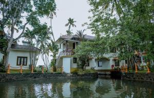 a house next to a body of water at The World Backwaters, Alleppey in Kumarakom