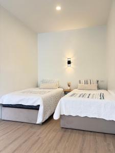 two beds in a bedroom with white walls and wood floors at Pomt Lagoon in Ban Khlong Dan